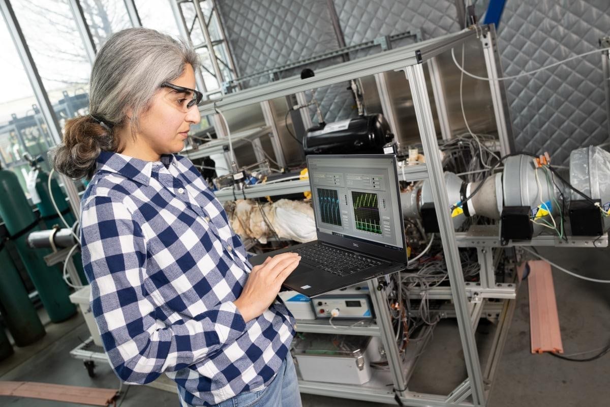 An engineer reviewing live instrument data on a laptop beside a test rig