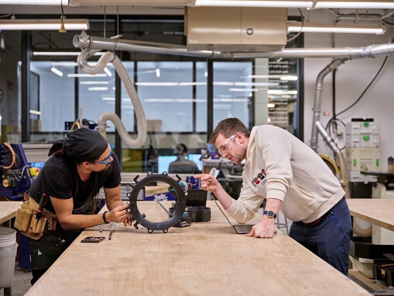 Two engineers examining a fabricated component in a makerspace
