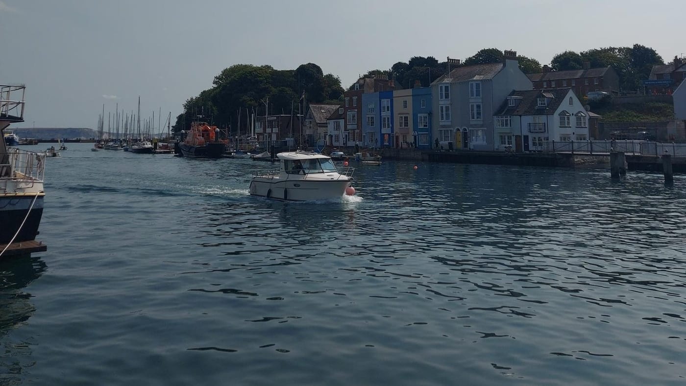 Weymouth harbor in Dorset, with painted terrace houses and moored fishing boats.