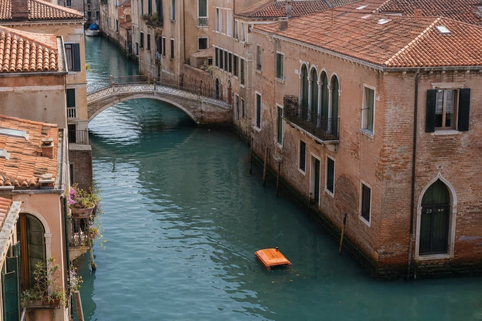 An orange WasteShark drone collecting litter on a narrow Venetian canal